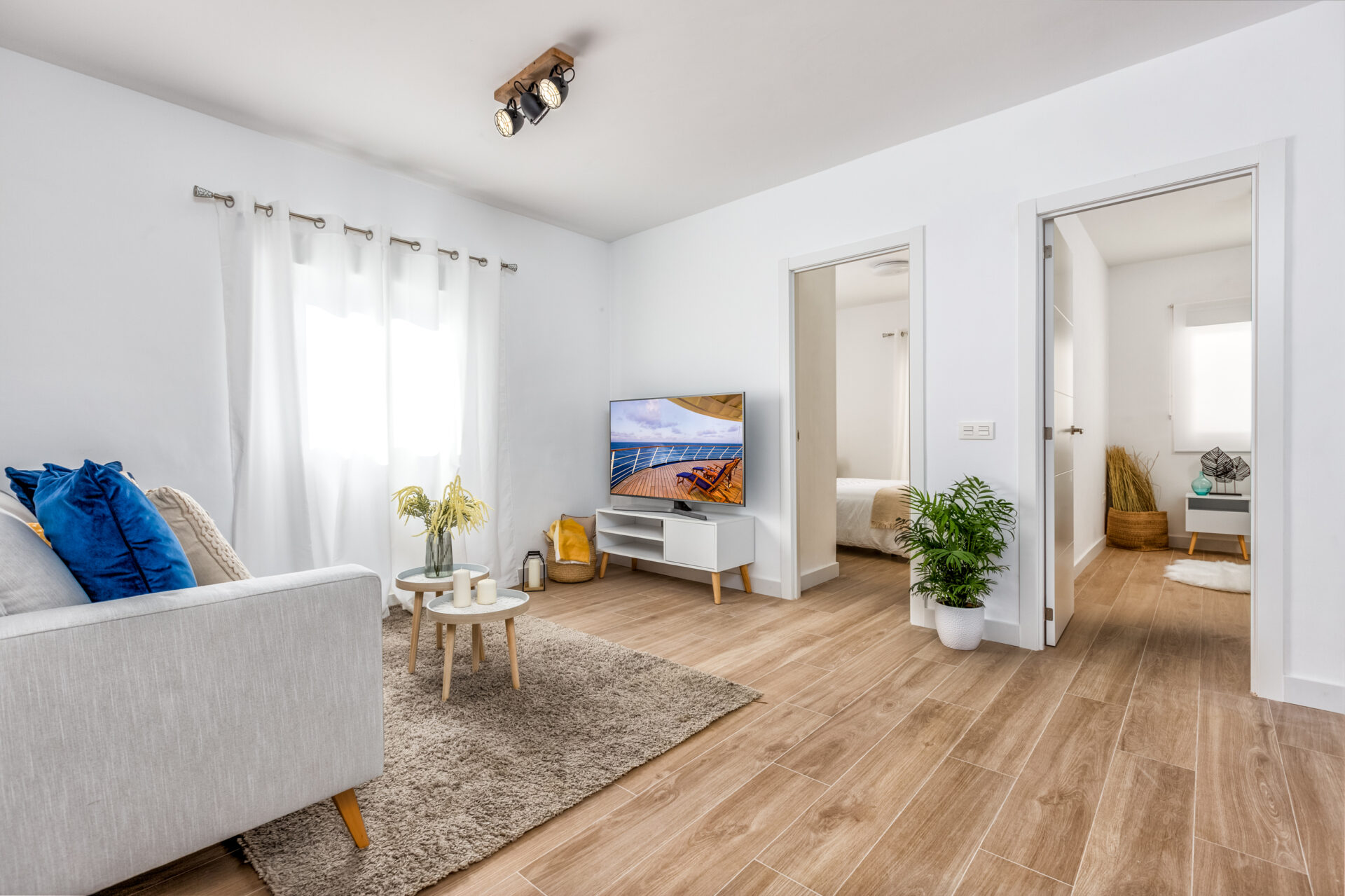 Sorolla 36: salón luminoso con suelo de madera y acceso a los dormitorios